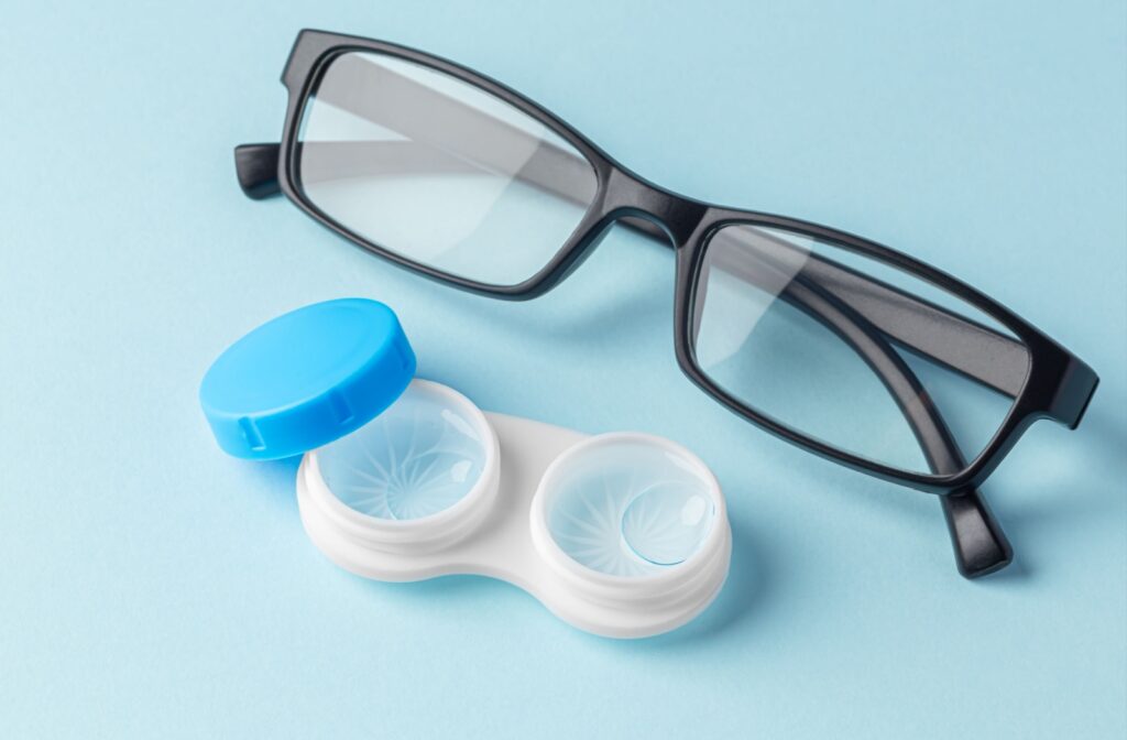 A closeup of an open contact lens container next to a pair of eyeglasses.