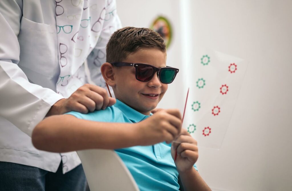 A child sitting down and doing a vision therapy session with their vision therapist looking on.