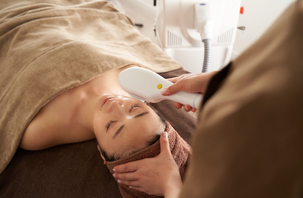 An adult lays down on a table while they undergo an IPL photofacial.